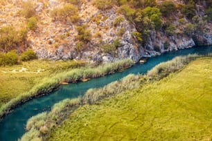 Aerial View of a winding river in the middle of a swampy area with a kayak traveling up the creek