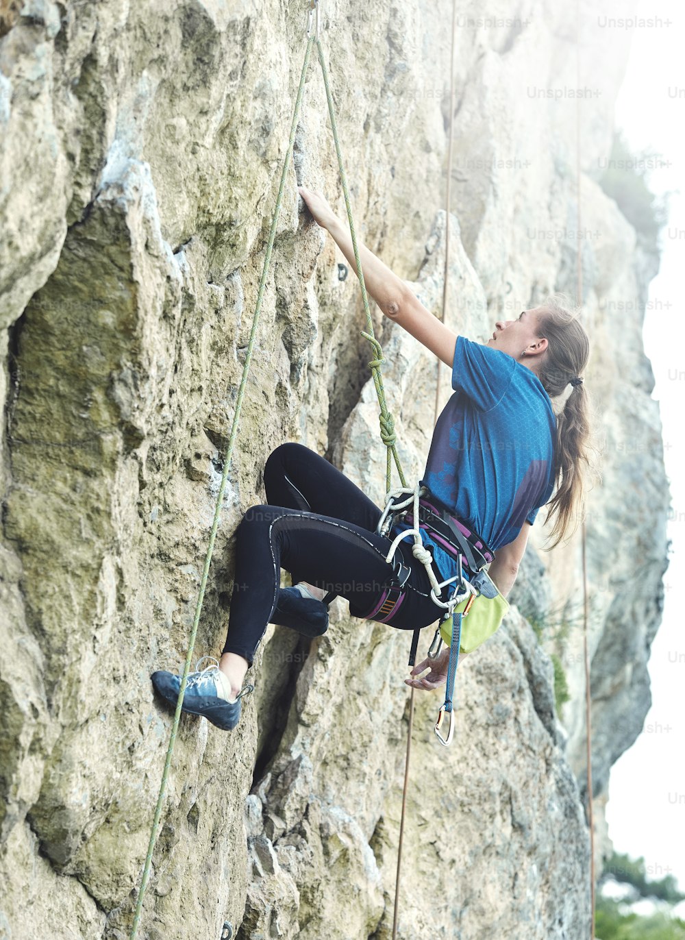 Erwachsene Frau Klettererin. Kletterer klettert auf eine Felswand. Frau macht harte Bewegung