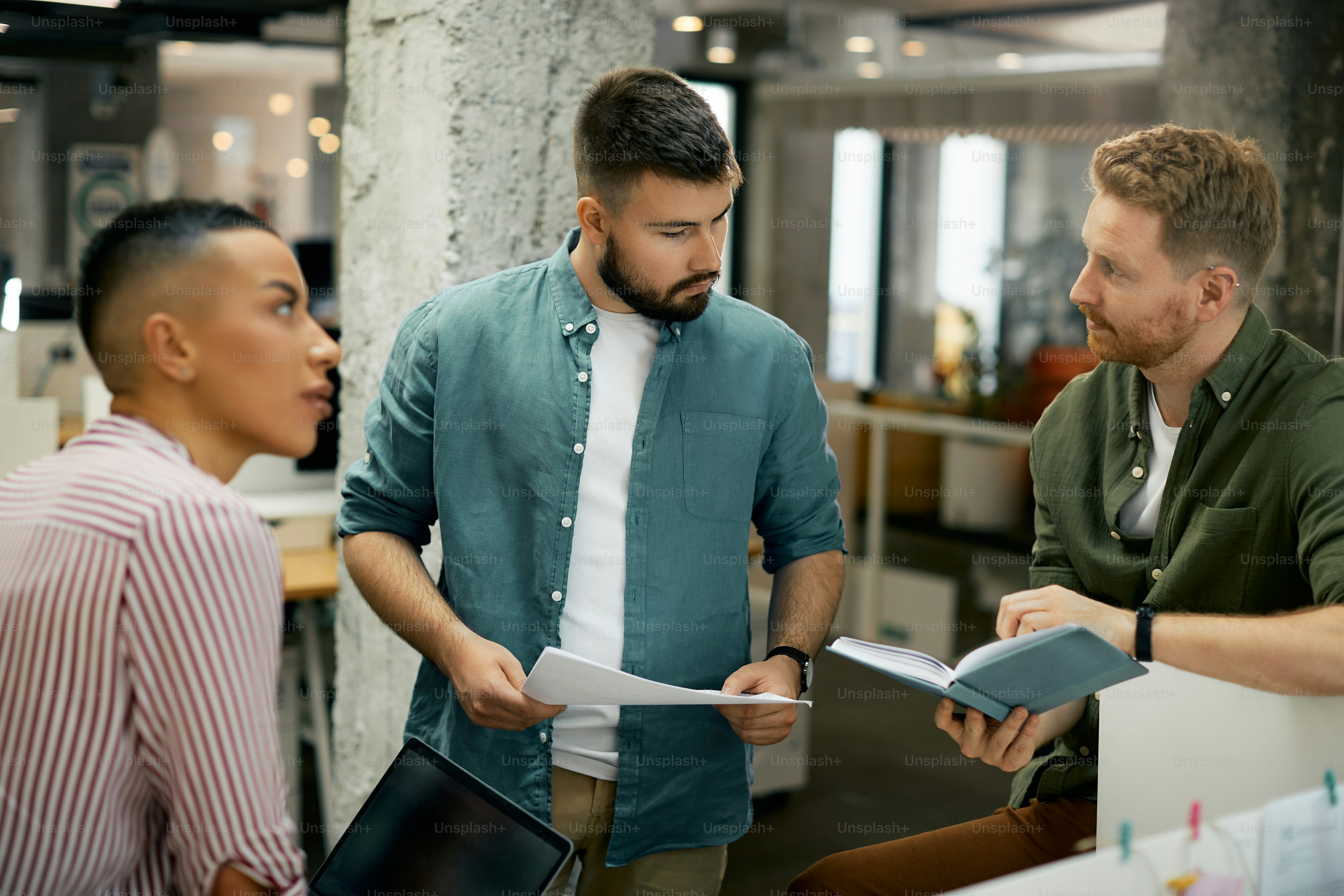 Young entrepreneur and his coworkers analyzing paperwork during a meeting in the office.