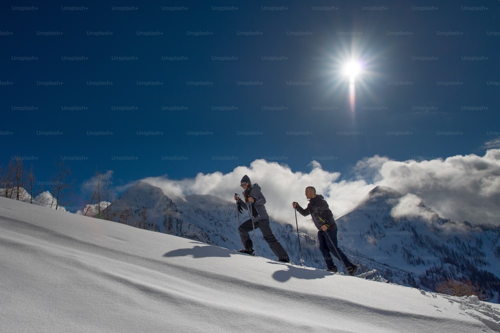 Racchette da neve praticate da un ragazzo e una ragazza sotto il caldo sole di montagna.
