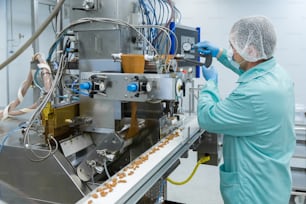 Pharmaceutical technician in sterile environment working with equipment at pharmacy industry