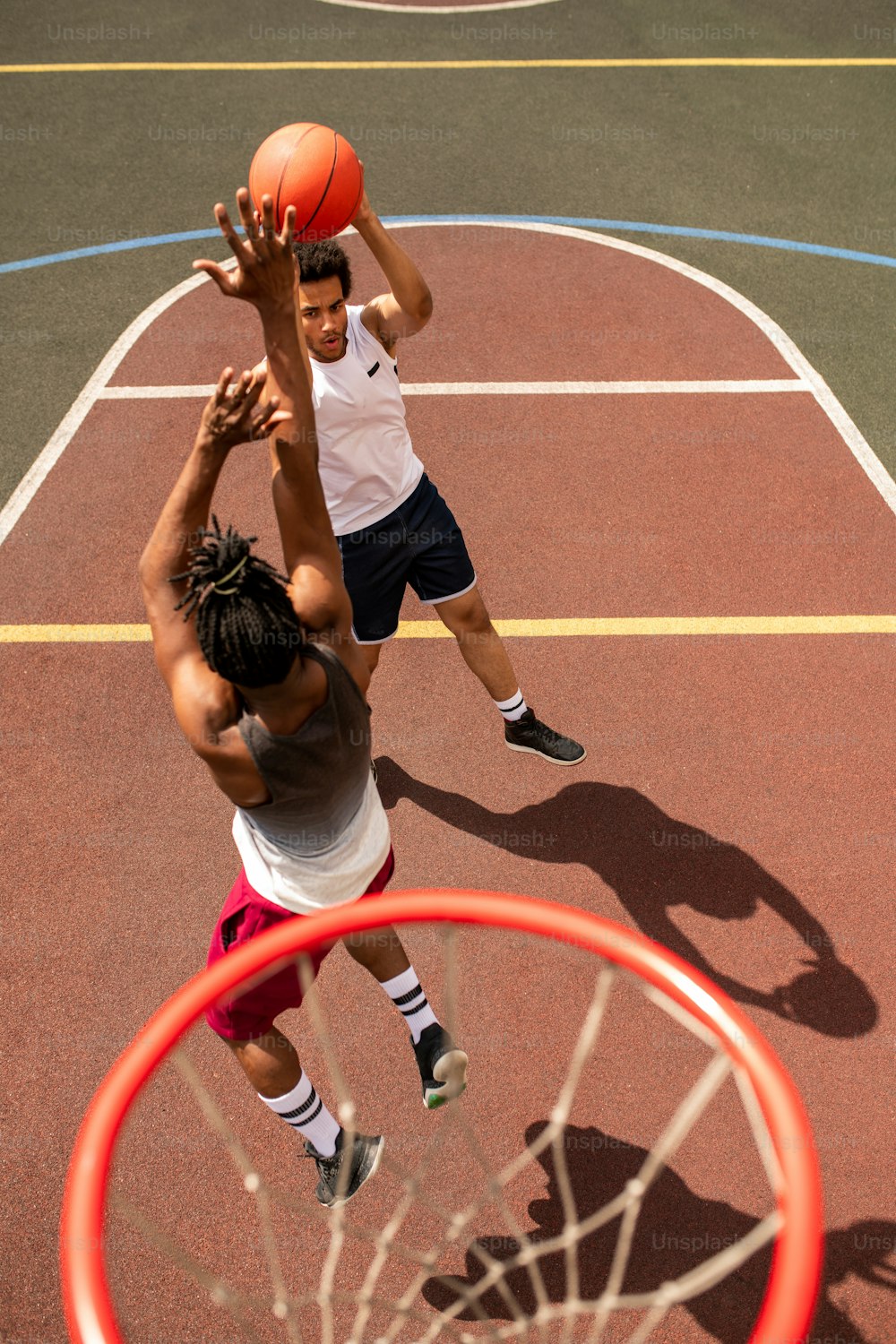 Uno de los jóvenes jugadores de baloncesto intercultural atacando el balón mientras su rival va a lanzarlo