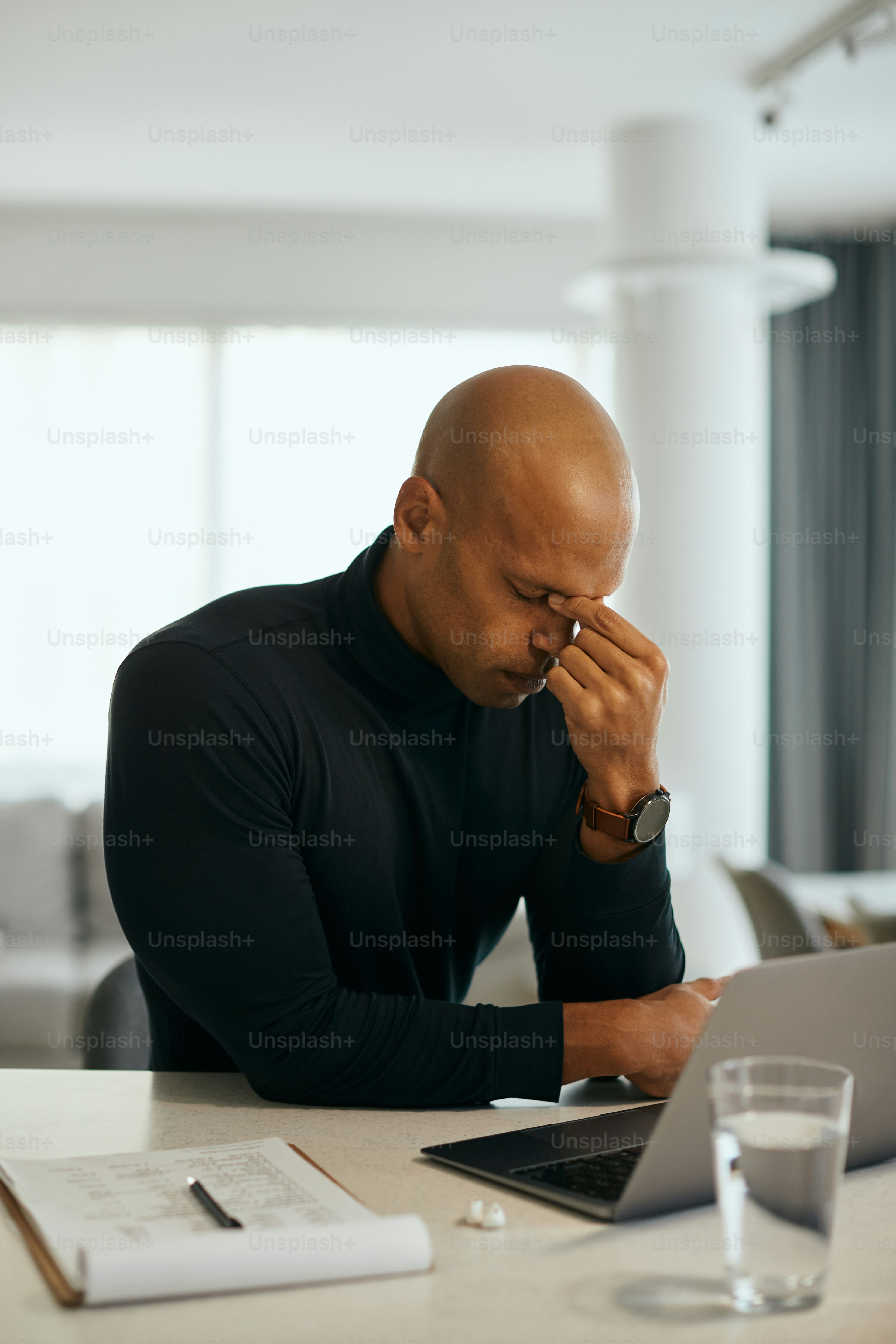Young African American entrepreneur having headache while working on laptop at home.