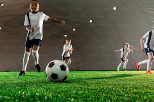 Ballon de football sur le terrain vert et petits joueurs qui courent vers lui pendant le match