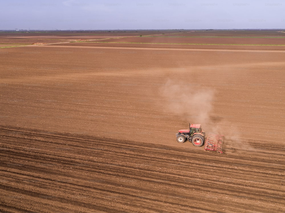 Aerial shot of a tractor cultivating field at spring