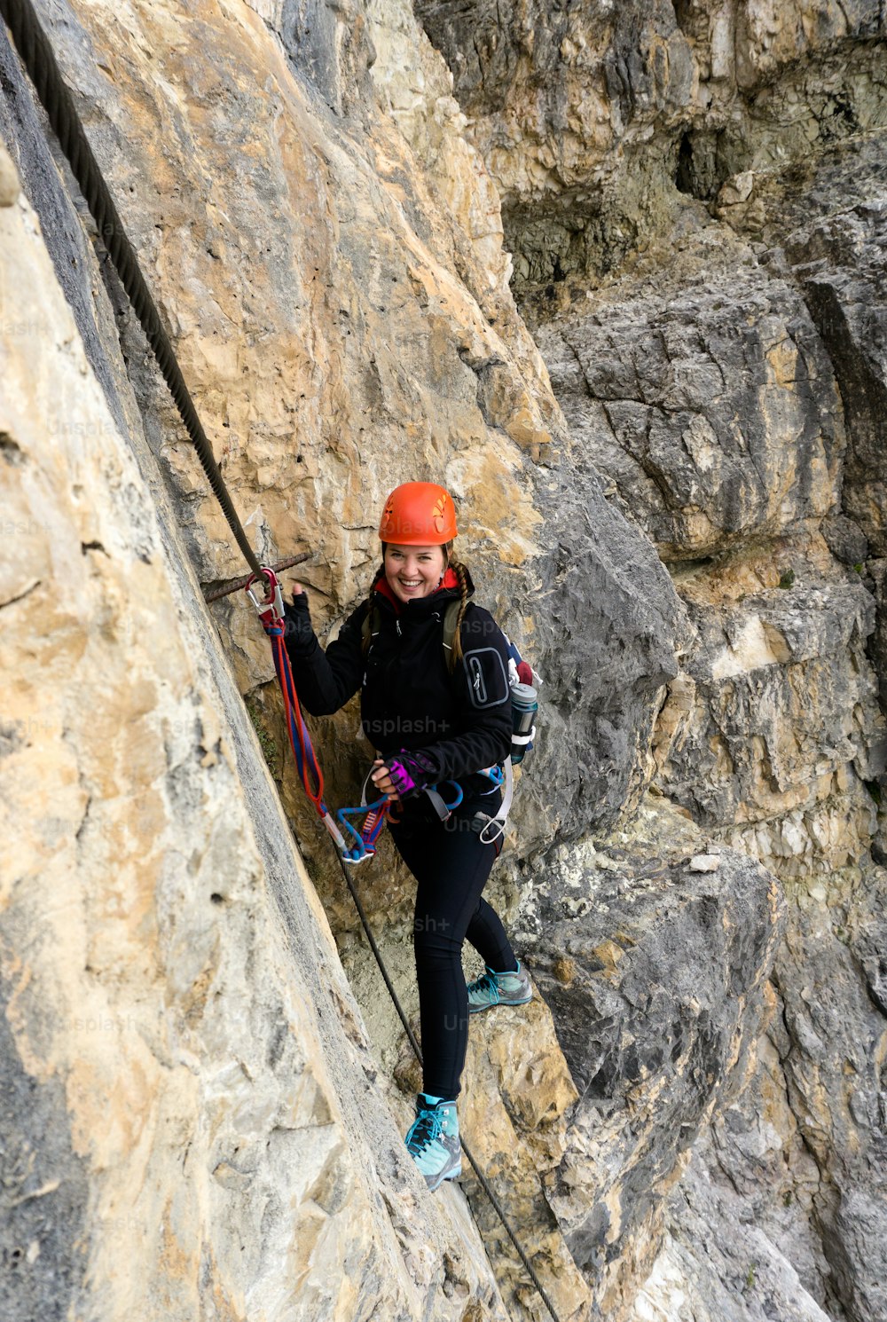 イタリアのドロミテの南チロルの露出した棚にあるフェラータ通りの若い女性登山家