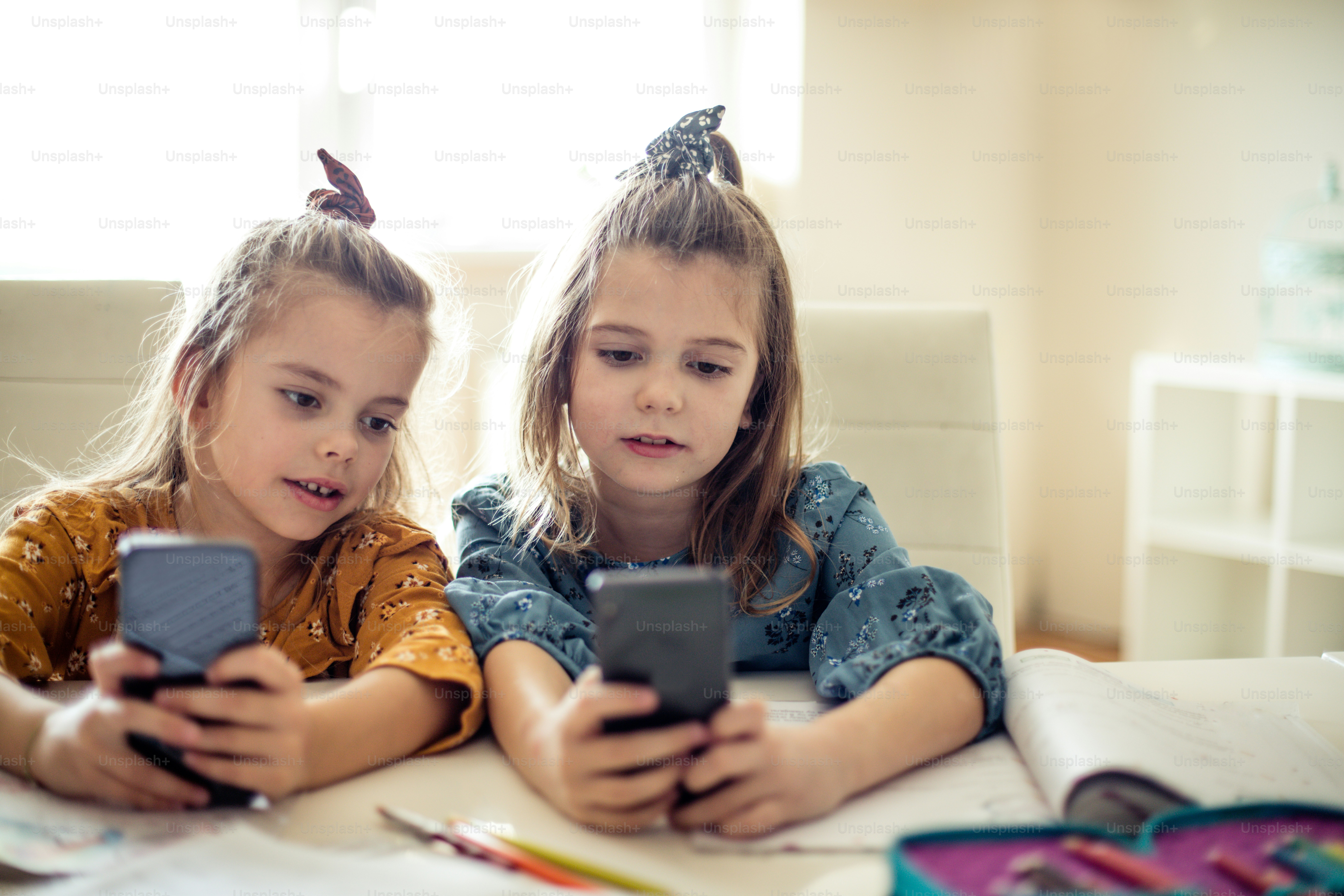 Which game do you play? Two little school girls using smart phone.