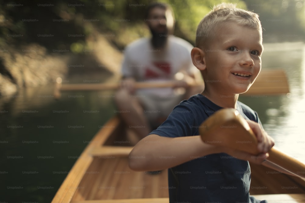 Menino aprendendo a remar canoa com seu pai em um belo dia ensolarado.