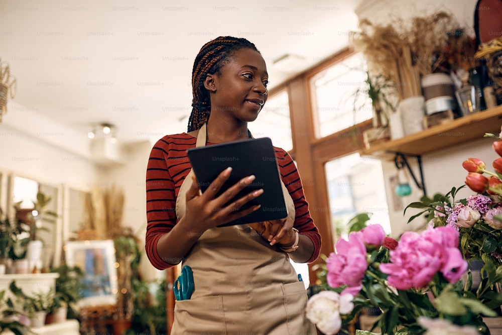 Young African American woman working on touchpad at her flower shop.