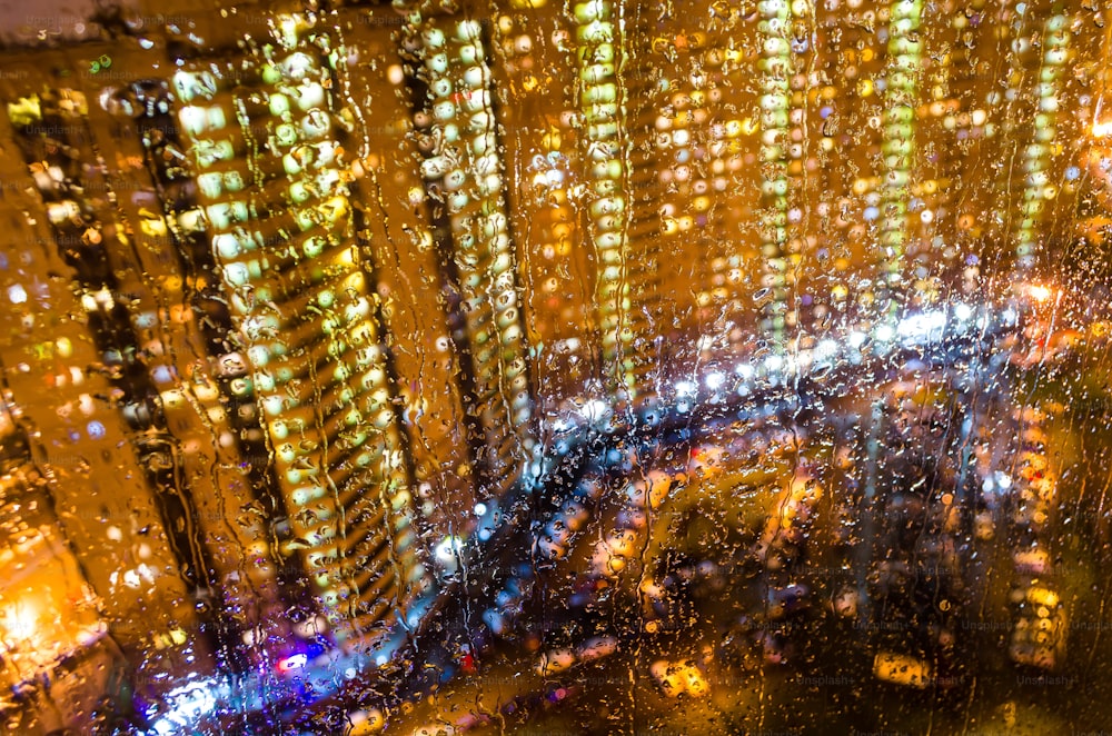 Chuva cai na janela com luzes bokeh de ruaQueda de chuva na janela com luzes bokeh de rua