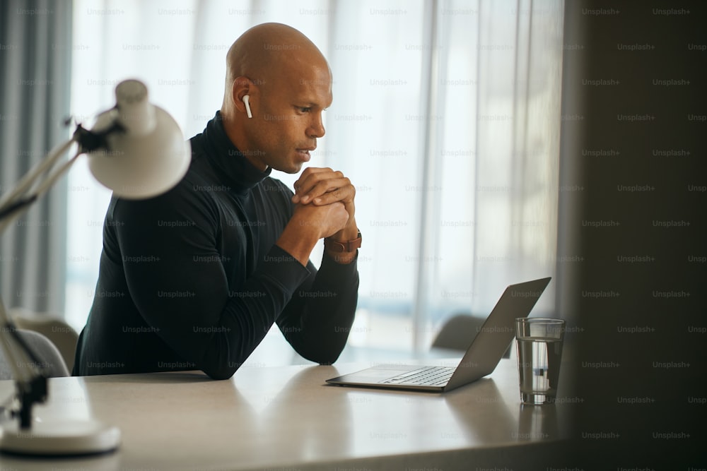 Joven empresario negro que usa una computadora portátil y habla mientras tiene una reunión de negocios en línea a través de una computadora portátil desde la oficina en casa. Espacio de copia.