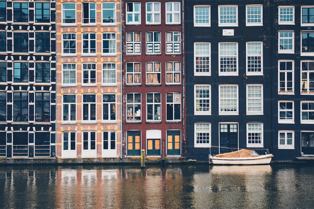 Row of typical houses and boat on Amsterdam canal Damrak with reflection. Amsterdam, Netherlands