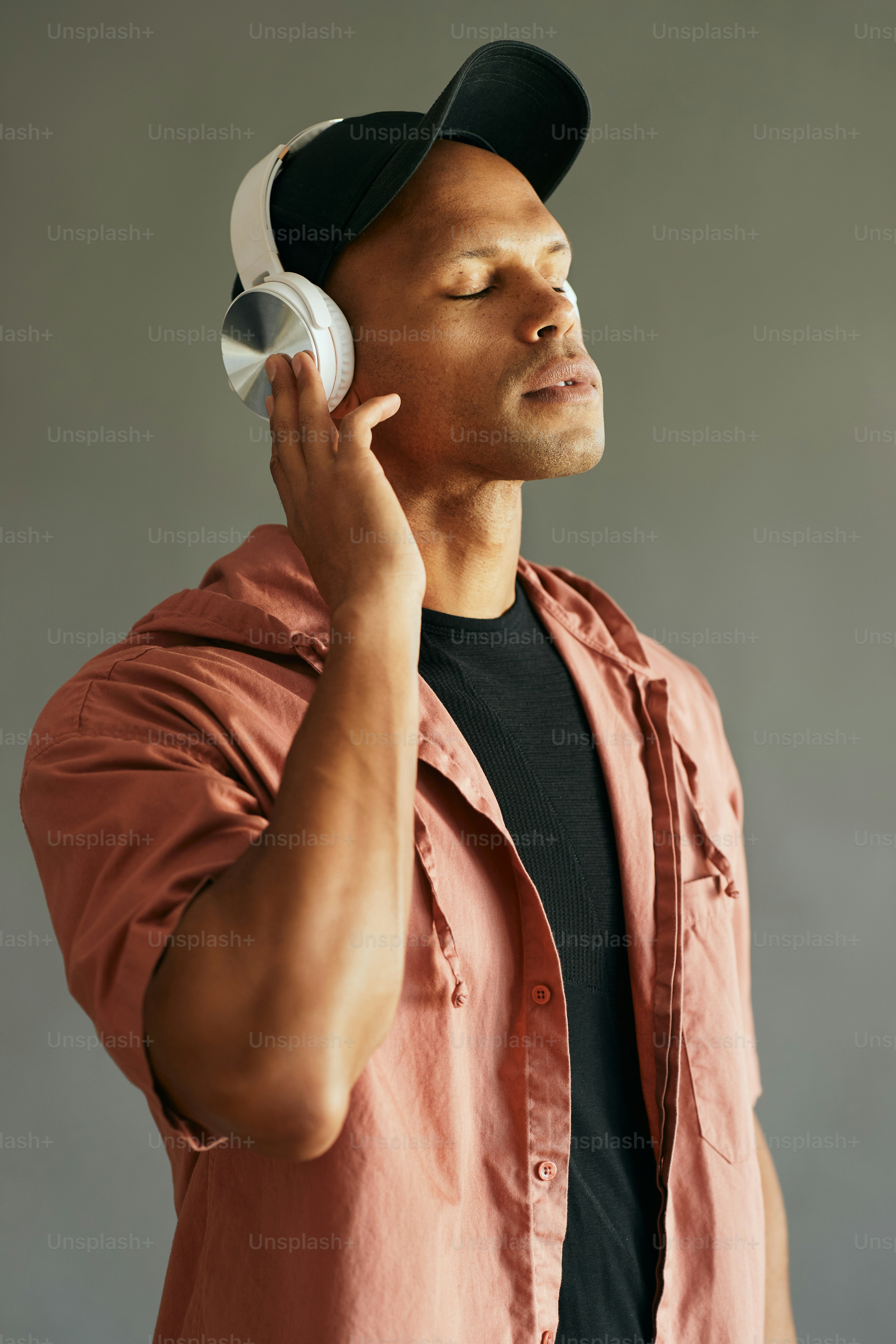 African American man wearing headphones and listening music wit his eyes closed.