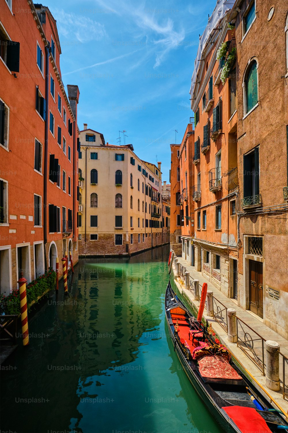 Narrow canal between colorful old houses with gondola boat in Venice, Italy