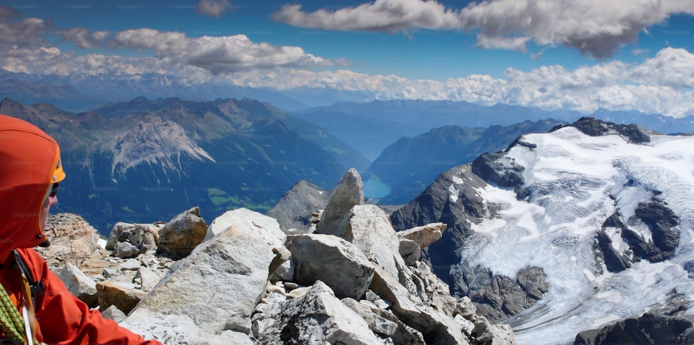 male mountain climber on a high alpine mountain peak admiring the wonderful mountain landscape view and panorama below him