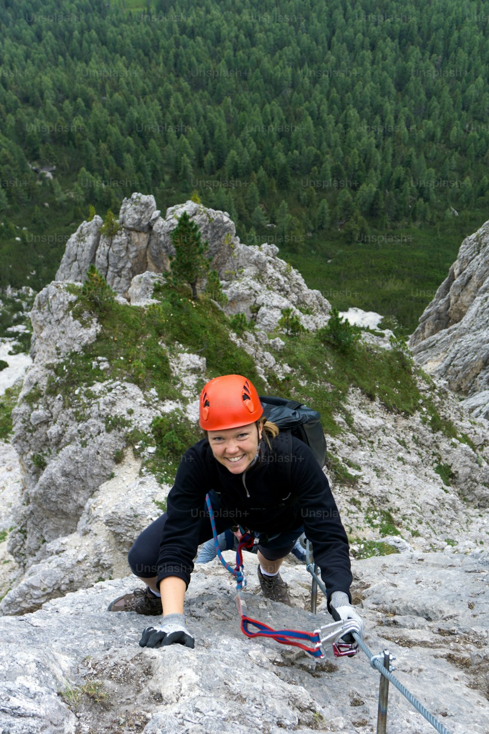 A woman in her twenties climbing a steep Via Ferrata in the Dolomites of Alta Badia