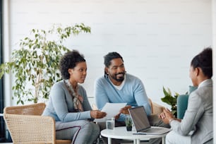 Smiling black couple communicating with their financial consultant while having a meeting in the office.