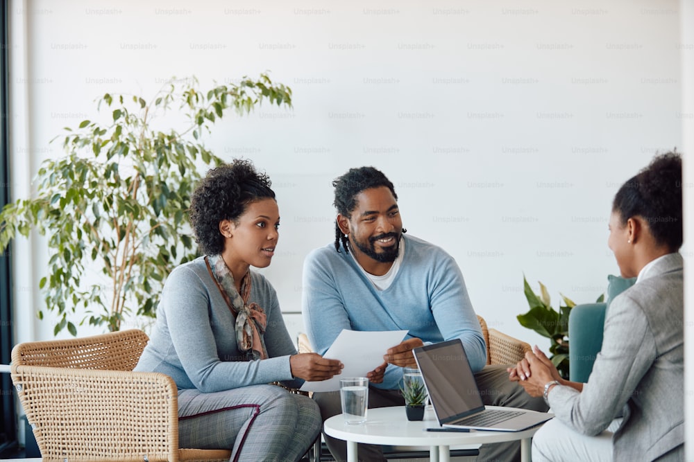 Smiling black couple communicating with their financial consultant while having a meeting in the office.