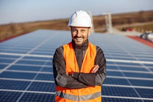 A handyman standing on the rooftop with solar panels and smiling at the camera.