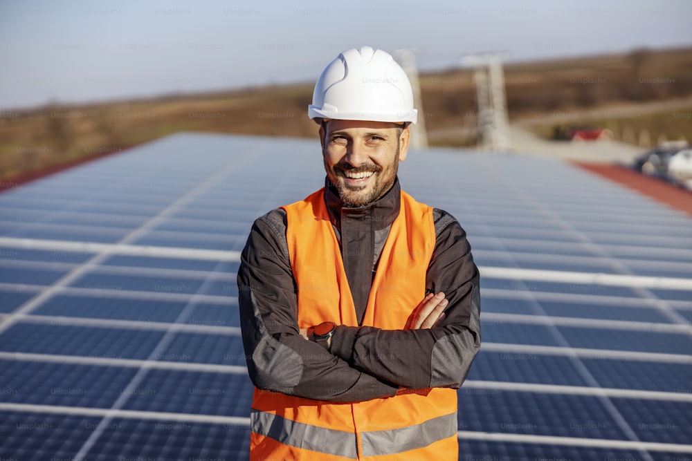 A handyman standing on the rooftop with solar panels and smiling at the camera.