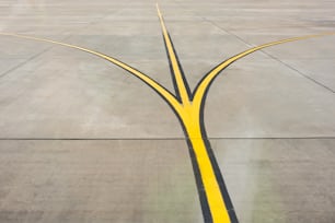 飛行場の滑走路でクローズアップされた黄色の方向ストリップフォーク