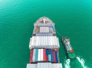 Remolcador y buque portacontenedores que va al puerto marítimo para descargar el contenedor en el puente grúa para logística, importación, exportación, envío o transporte.
