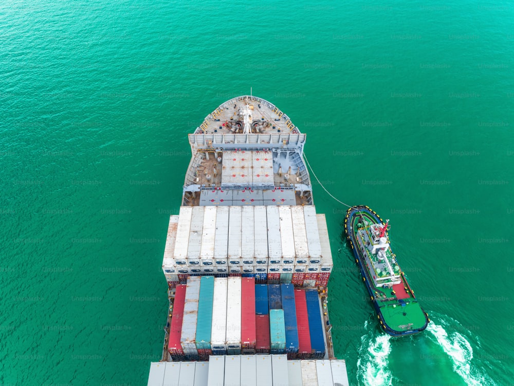 Tugboat and container ship going to seaport for unload container at crane bridge for logistics, import export, shipping or transportation.