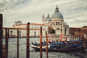 Gondola boats in Venice Italy with gorgeous view of Basilica Santa Maria della Salute. Venice is famous travel destination in Italy for its unique cityscape and culture.