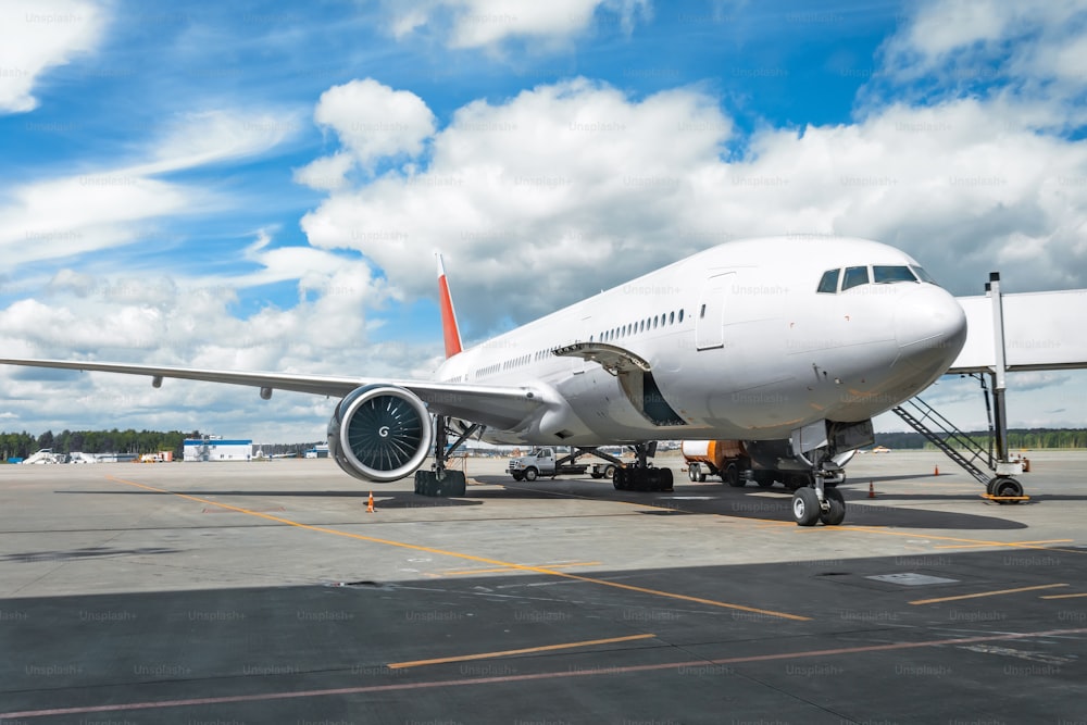 Passenger aircraft with boarding stairs, waiting for boarding passengers and baggage before the flight, summer airport trip