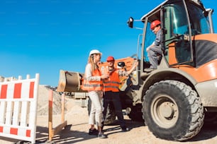 Civil engineer and worker discussion on road construction site, woman and man