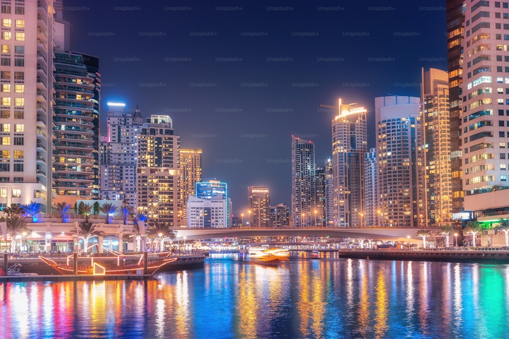Vista notturna colorata della famosa attrazione turistica della città di Dubai - porto marittimo di Marina e grattacieli illuminati. Viaggi e immobili negli Emirati Arabi Uniti