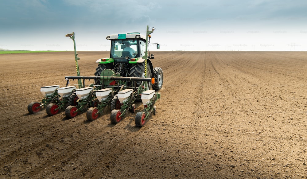 Farmer with tractor seeding  crops at agricultural field