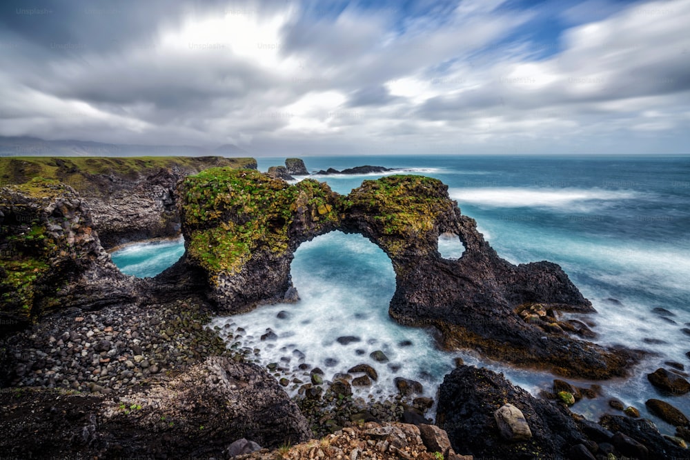 Amazing stone arch Gatklettur basalt rock on Atlantic coast of Arnarstapi in Iceland. The famous natural form arch attracts tourist to visit west of Iceland.