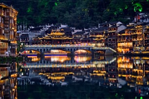 Chinese tourist attraction destination - Feng Huang Ancient Town (Phoenix Ancient Town) on Tuo Jiang River illuminated at night. Hunan Province, China