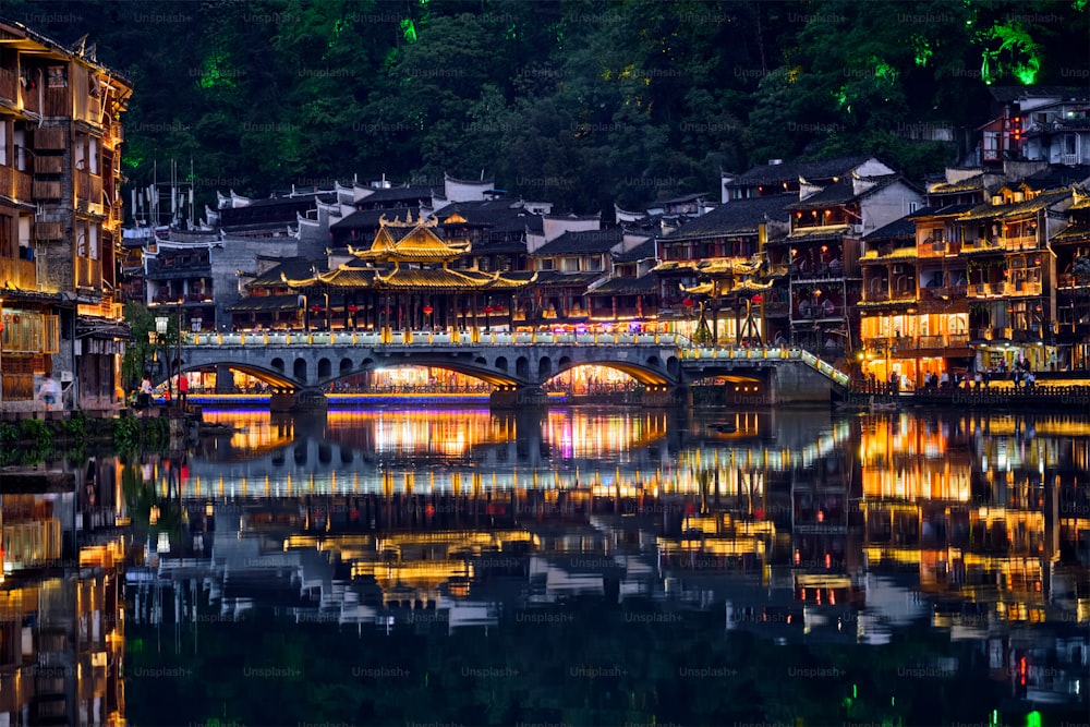 Chinese tourist attraction destination - Feng Huang Ancient Town (Phoenix Ancient Town) on Tuo Jiang River illuminated at night. Hunan Province, China