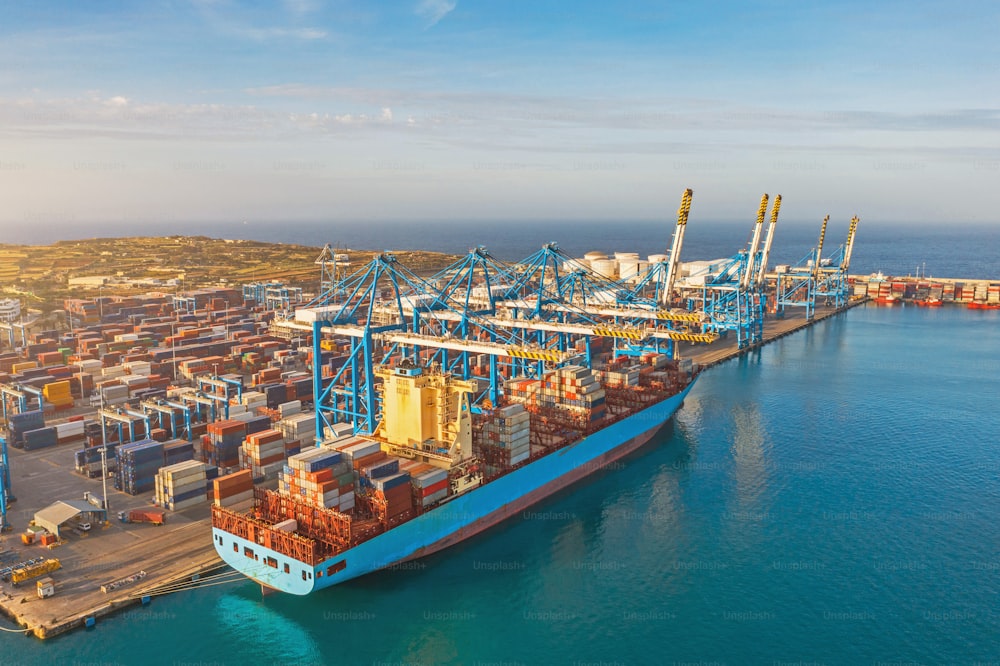 Luftbild riesiger Frachtliner, der am Pier am Hafen vor Anker liegt und Container entlädt