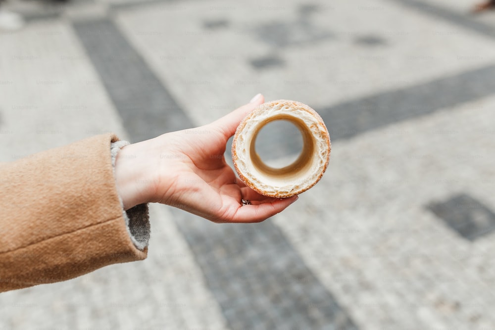 Female hand holding traditional czech cookie called trdelnik On a background of stone pavers