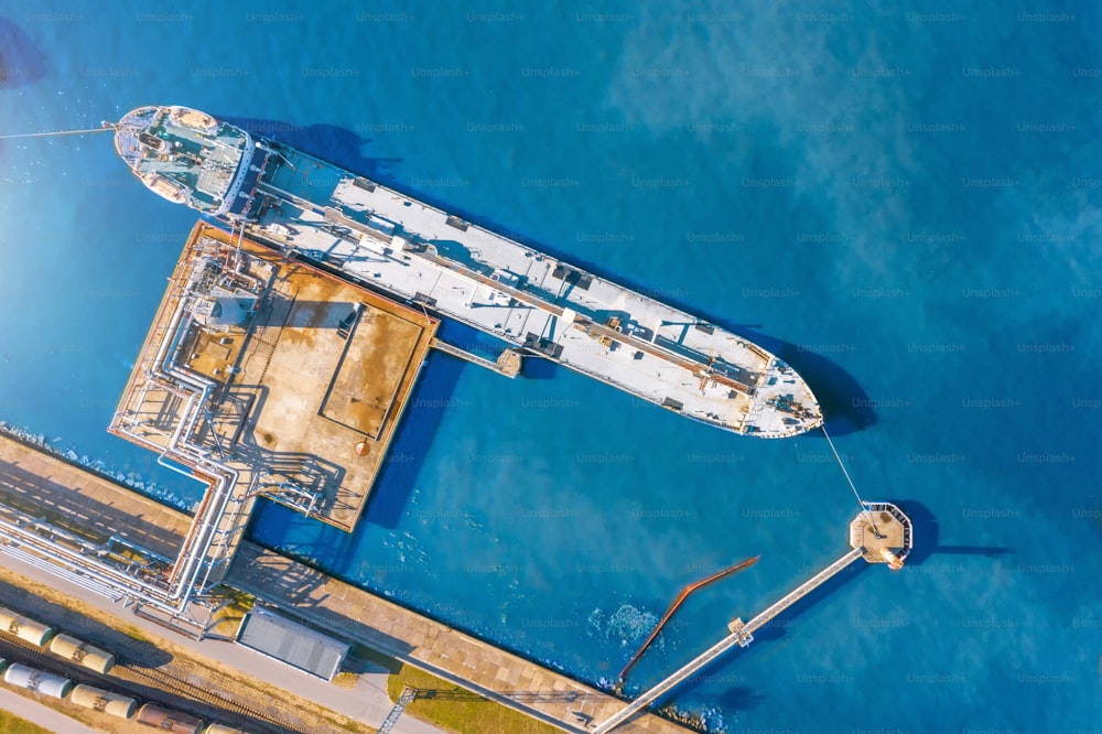 Aerial top view tanker at unloading in a large bulk port liquid cargo, oil, liquefied gas, fuel.