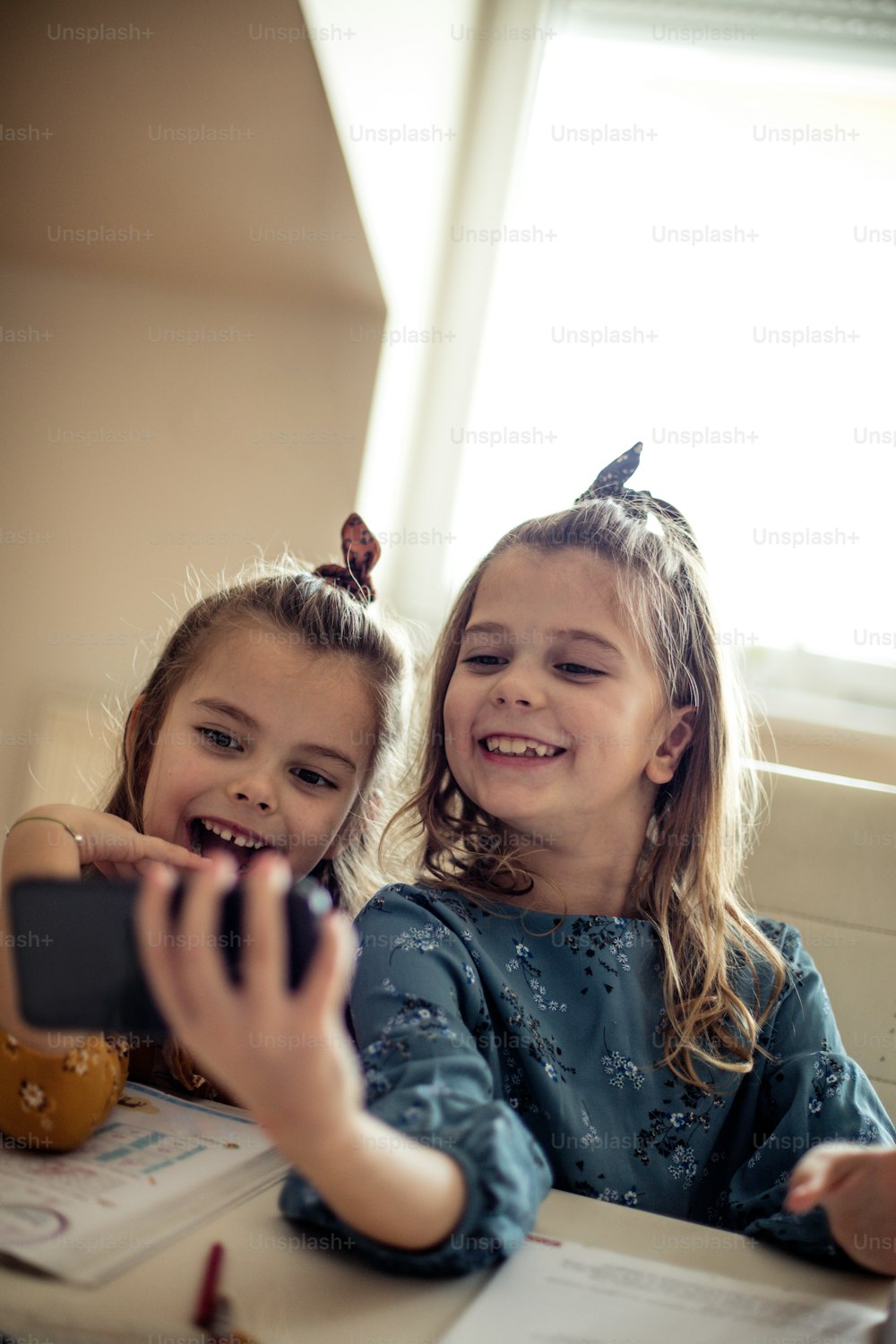 Lächeln für Foto. Zwei kleine Schulmädchen machen ein Selbstporträt.