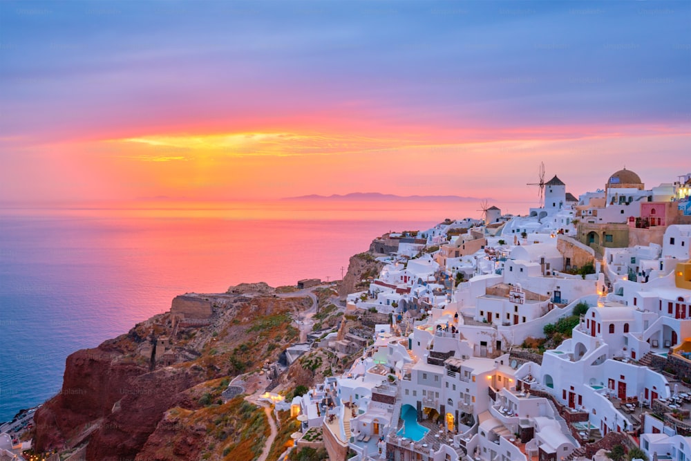 Berühmter griechischer ikonischer Selfie-Spot Touristenziel Oia Dorf mit traditionellen weißen Häusern und Windmühlen auf der Insel Santorini bei Sonnenuntergang in der Dämmerung, Griechenland