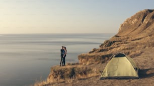 La pareja romántica de pie en el borde de la montaña cerca del mar