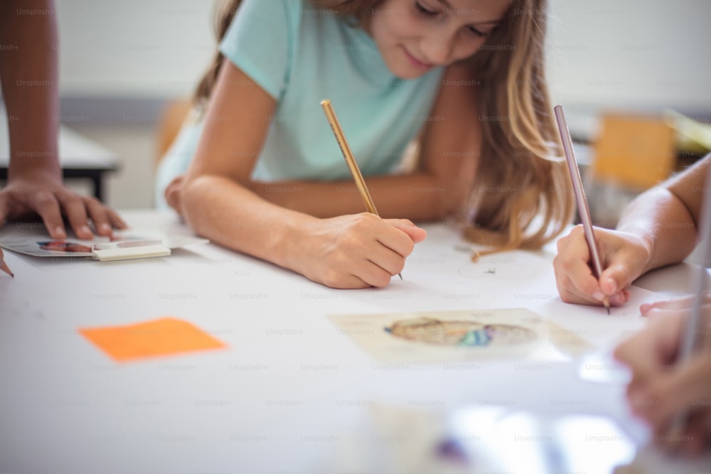 Adolescentes estudiantes sentados en el aula y escribiendo. La atención se centra en las manos.
