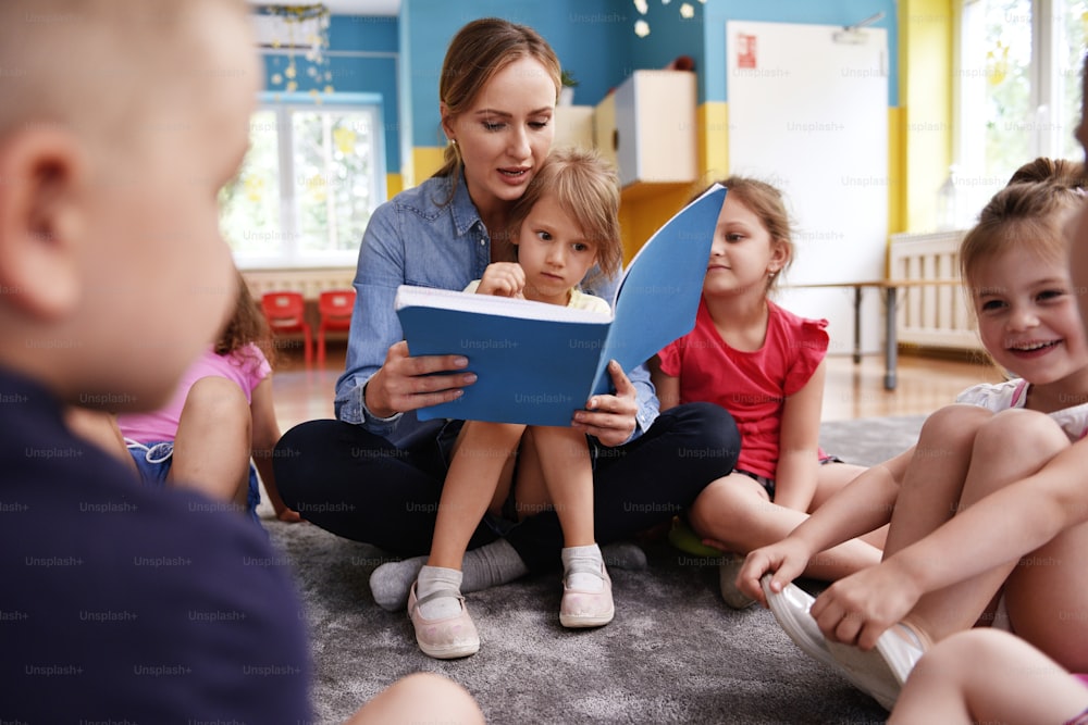Kids and teacher reading a book together in the preschool