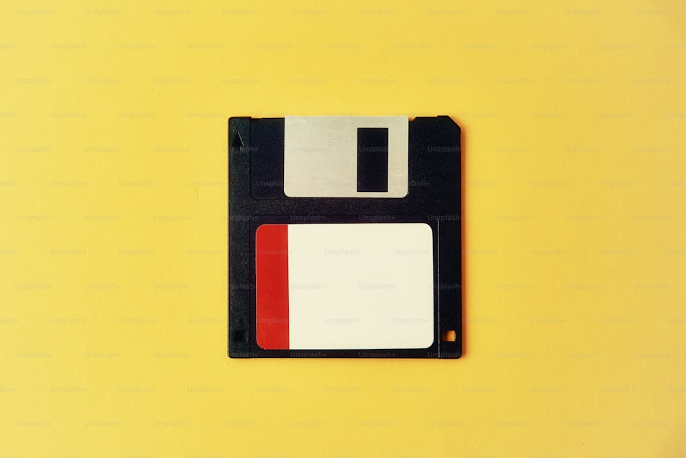 Dischetto floppy nero su sfondo giallo. Dischetto del computer dell'annata, primo piano