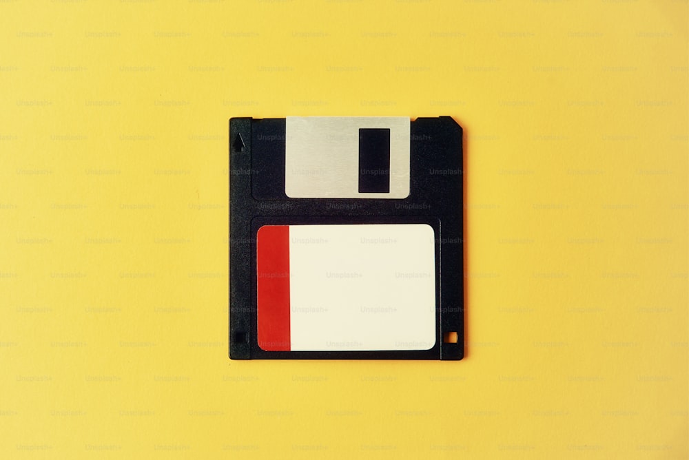 Black floppy diskette on yellow background. Vintage computer diskette, close up