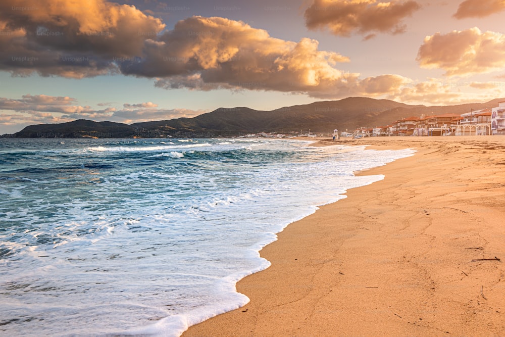 Vista panorâmica dramática da icônica cidade turística de Sarti e da famosa praia de areia longa e vazia na hora do pôr do sol. Férias em Halkidiki, Grécia