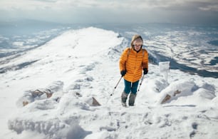 Young woman climbing on the snowy mountain ridge.