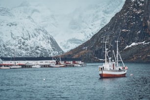 Barco de pesca en el pueblo pesquero de Hamnoy en las islas Lofoten, Noruega con casas rorbu rojas. Con la nieve cayendo