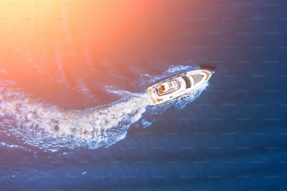 Il lancio della barca ad alta velocità galleggia alla luce del sole nell'ocrean, vista aerea dall'alto