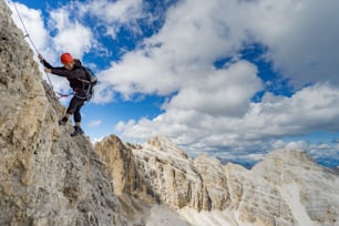Horizontal view of a female mountain climber on a steep Via Ferrata in the Italian Dolomites with a great view behind